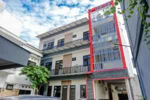 a tall white building with a red balcony at OYO Life 2744 Guest House Qudsi in Malang