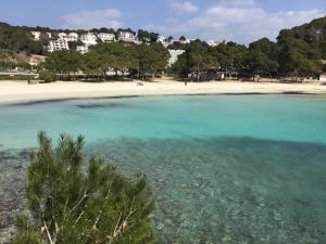 una playa con agua turquesa y árboles y casas en Apartamento Gama 1 habitación, en Cala Galdana