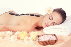 Uma mulher deitada numa cama de massagem com uma tigela de cosméticos. em Schloss Kirchham em Kirchham