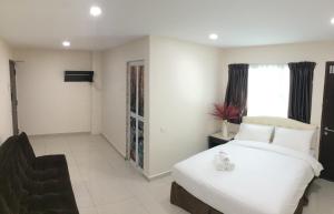 een slaapkamer met een groot wit bed en een stoel bij Sam Hotel in Sitiawan