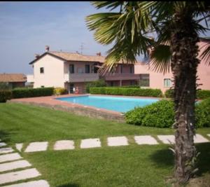 a swimming pool in front of a house with a palm tree at Mahatma Residence lake View in Lazise