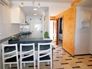 a kitchen with a black counter and two white stools at Apartment Sol Y Mar by Interhome in Altea