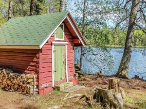 ein rotes Haus mit einer grünen Tür und einem Holzhaufen in der Unterkunft Holiday Home Heinälampi by Interhome in Laakkii
