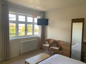 a bedroom with a bed and two chairs and windows at Picaroons Bed and Breakfast in Sheringham