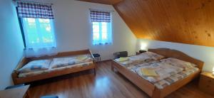 two beds in a large room with two windows at Penzión Jánošíkova Krčma in Ružomberok +20 photos
