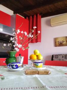 una mesa con un bol de fruta y un jarrón de limones en Mansarda mare red, en Sciacca