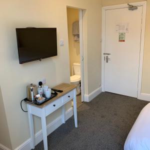 a room with a desk and a tv on a wall at Royal Oak Hotel in Leicester