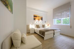 Habitación blanca con cama y sofá en NeoMagna Madrid en Madrid