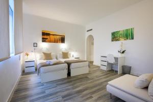 Habitación blanca con 2 camas y sofá en NeoMagna Madrid en Madrid