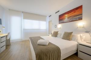 a white bedroom with a bed and a desk at NeoMagna Madrid in Madrid