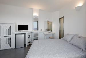 a bedroom with a bed and a desk with a television at Suites of the Gods Cave Spa Hotel in Megalokhori