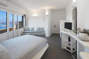 a white bedroom with a bed and a television at Suites of the Gods Cave Spa Hotel in Megalokhori