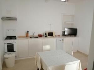 a white kitchen with a table and a microwave at Casas do Cinema I in Mindelo