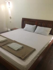 Una cama con sábanas blancas y dos toallas. en Dream Home Hostel en Vientián