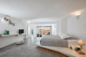 a white bedroom with a large bed and a television at Suites of the Gods Cave Spa Hotel in Megalokhori