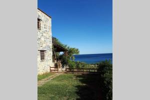 an old building with the ocean in the background at Traditional stone house by the sea... in Kapetanianá