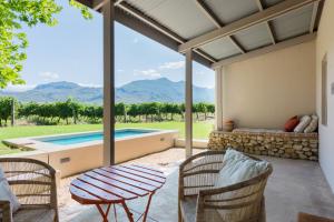 un patio con tavolo, sedie e piscina di La Chataigne Wines & Guest Cottages a Franschhoek