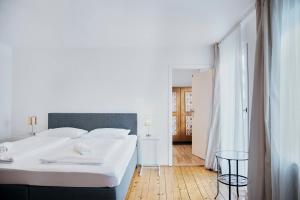 a white bedroom with a large bed and a table at Gasthof Wastlwirt in Salzburg