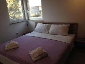 a bedroom with two towels on a bed with two windows at Guesthouse Bencun Medulin in Medulin