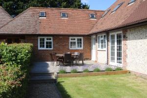 a house with a patio with a table and chairs at Flintstone Cottages in Chichester