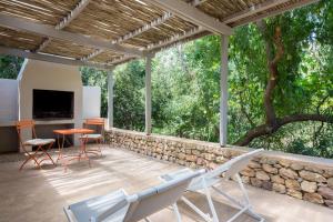 eine Terrasse mit Stühlen, einem Tisch und einer Steinmauer in der Unterkunft La Chataigne Wines & Guest Cottages in Franschhoek