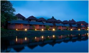 a row of lodges next to a river at night at SwaSwara Gokarna - CGH Earth in Gokarna