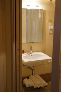 ein Badezimmer mit einem Waschbecken, einem Spiegel und Handtüchern in der Unterkunft LOCANDA IL CANOVACCIO in Campiglia Marittima