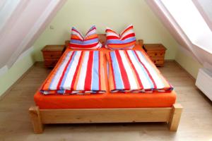 uma cama com almofadas vermelhas brancas e azuis num sótão em Ferienhaus Schild em Elsterheide