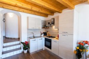 a kitchen with white cabinets and a wooden ceiling at Ap. Artù - Lago di Garda in Tremosine Sul Garda