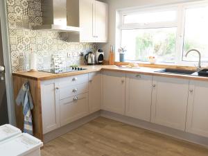 a kitchen with white cabinets and a sink and a window at Waters Edge in Haverfordwest