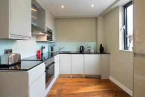 a kitchen with white cabinets and a wooden floor at Victoria One in London