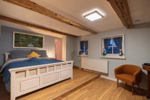 a bedroom with a bed and a chair and two windows at Gesindehaus Börnecke in Börnecke