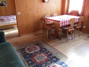 a dining room with a table and chairs and a rug at Gutenbrunnenstrasse 94 in Lenk