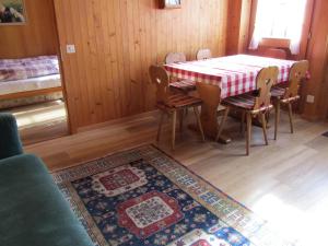 comedor con mesa, sillas y alfombra en Gutenbrunnenstrasse 94, en Lenk
