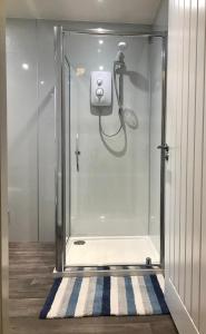 a shower in a bathroom with a glass door at The Steamboat - A Flat with Amazing Harbour Views in Wick