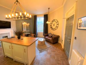 a kitchen and living room with a clock on the wall at The Leeming at Claremont Apartments in Leeds