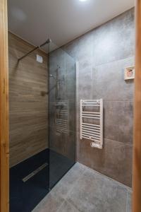 uma casa de banho com um chuveiro e uma porta de vidro em ODYSSEE CRC04 - Charmant appartement sur les pistes em La Toussuire