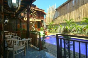 a resort with a pool and chairs next to a building at Tropical Canggu Hostel in Canggu