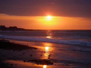 a sunset on a beach with the ocean at Klitmøller Badehotel in Klitmøller