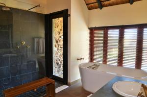 bagno con vasca, doccia e lavandino di Tshukudu Bush Lodge a Ledig