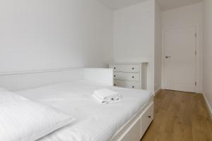 biała sypialnia z białym łóżkiem i komodą w obiekcie Rozłogi Sunny Apartment w Warszawie