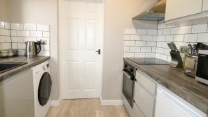 uma cozinha com um lavatório e uma máquina de lavar roupa em Flat 2 Castle Street Serviced Apartments em Telford
