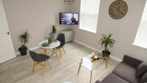 a living room with a table and chairs and a clock at Flat 2 Castle Street Serviced Apartments in Telford
