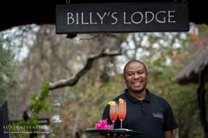 a man holding a tray with two champagne glasses at Ezulwini Game Lodges in Balule Game Reserve