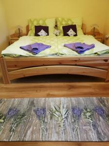 een bed met paarse lakens en kussens erop bij Levendulás ház in Becsehely