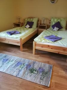twee bedden in een kamer met een tapijt op de vloer bij Levendulás ház in Becsehely