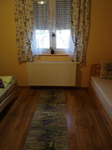 1 dormitorio con ventana con cortinas y alfombra en Levendulás ház, en Becsehely