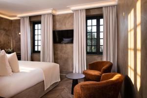 a hotel room with a bed and two chairs at Hôtel Saint-Delis - La Maison du Peintre - Relais & Châteaux in Honfleur