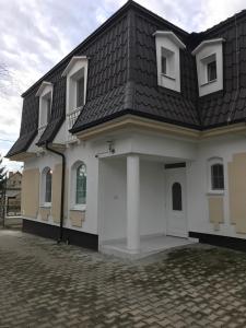 ein weißes Haus mit schwarzem Dach in der Unterkunft PENZION ANIKO DIAKOVCE-ŠAĽA in Diakovce