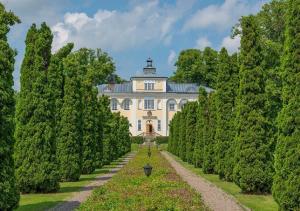 une grande maison blanche avec des arbres devant elle dans l'établissement Haga Slott, à Enköping